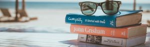 stack of books with sunglasses on a beach
